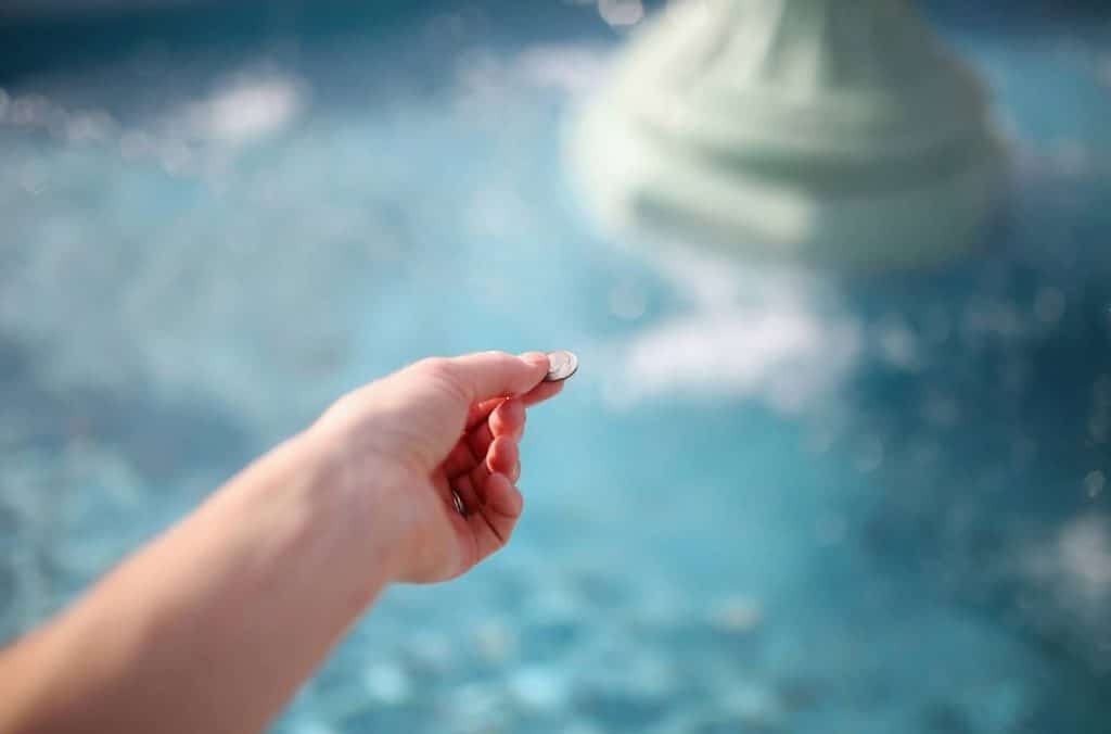 personne qui jette une pièce dans une fontaine