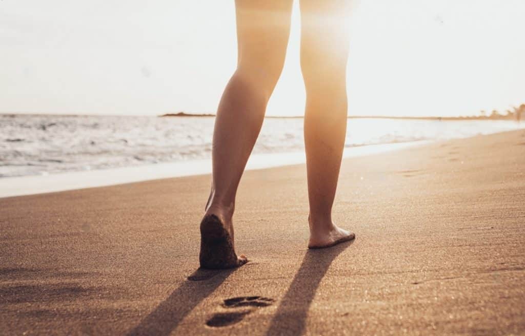 une femme qui marche pieds nus sur la plage au bord de mer