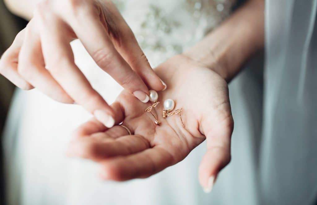 femme qui tient des boucles d'oreilles en perles 